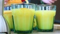 The cook pours orange juice into transparent glasses